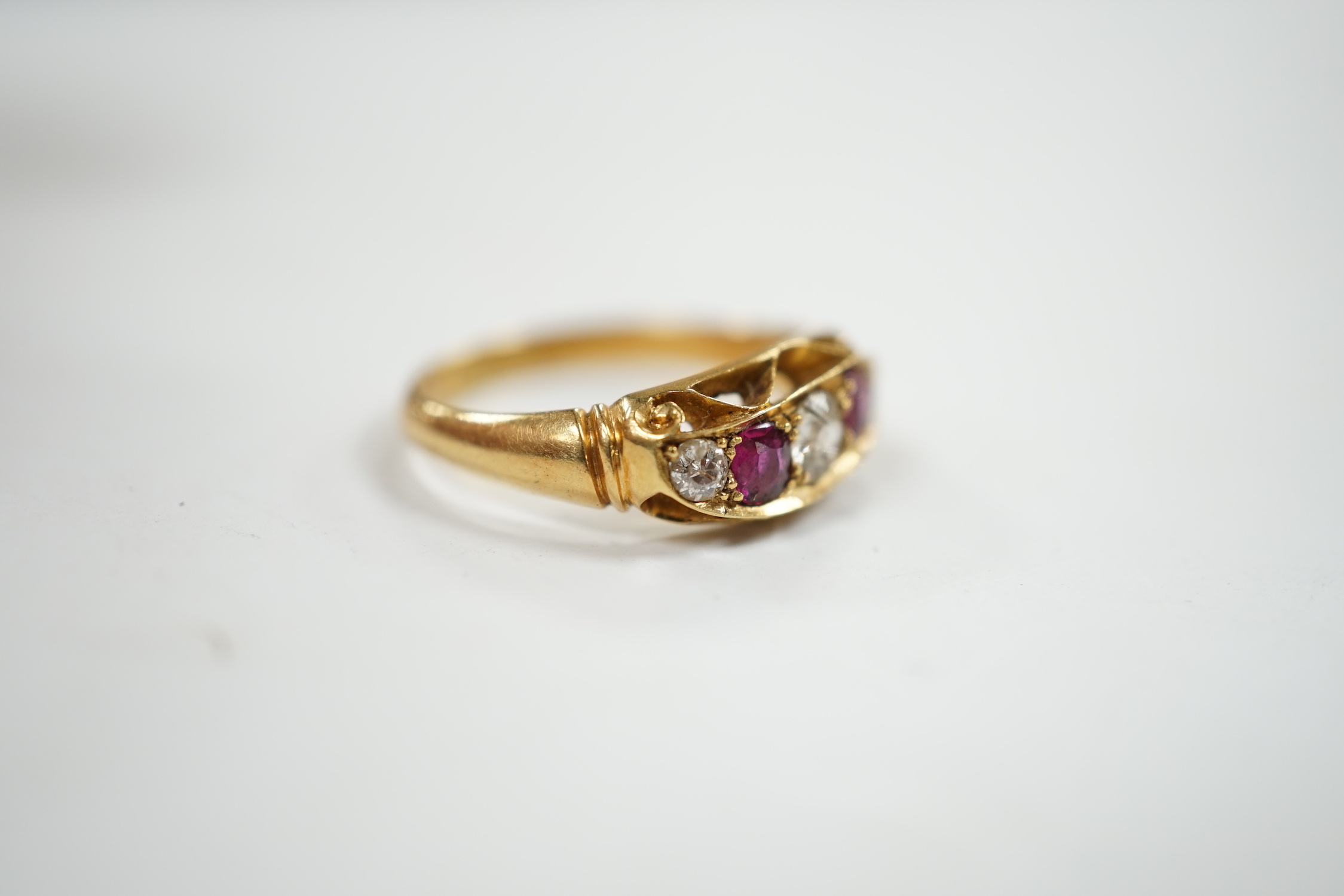A George V 18ct gold, three stone diamond and two stone ruby set half hoop ring, size N, gross weight 3.8 grams.
